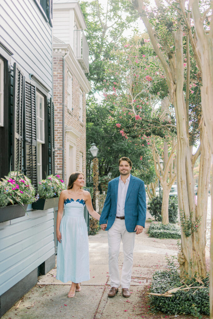 Couples walks by pink flowers and crepe myrtles in Charleston