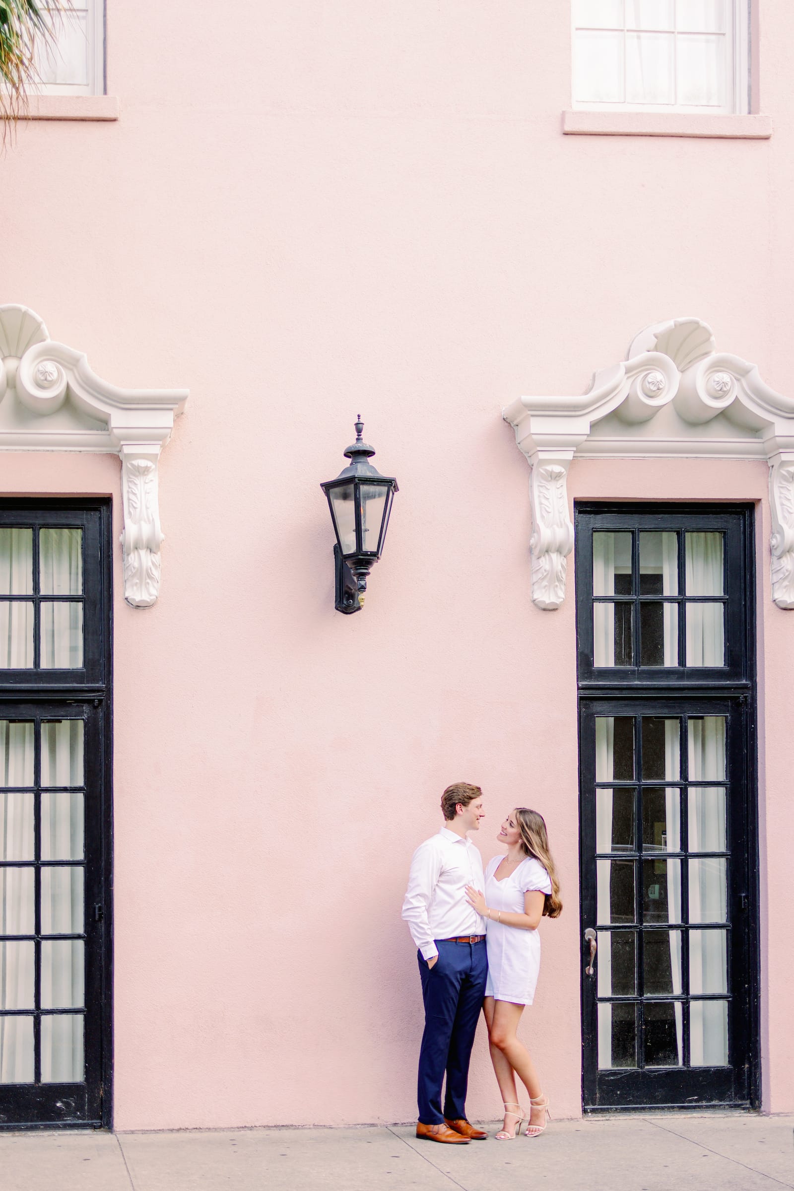 couple standing together against pink wall in downtown charleston